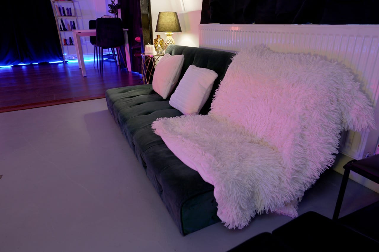 Relaxation lounge of the penthouse with a velvet sofa and white faux-fur throw