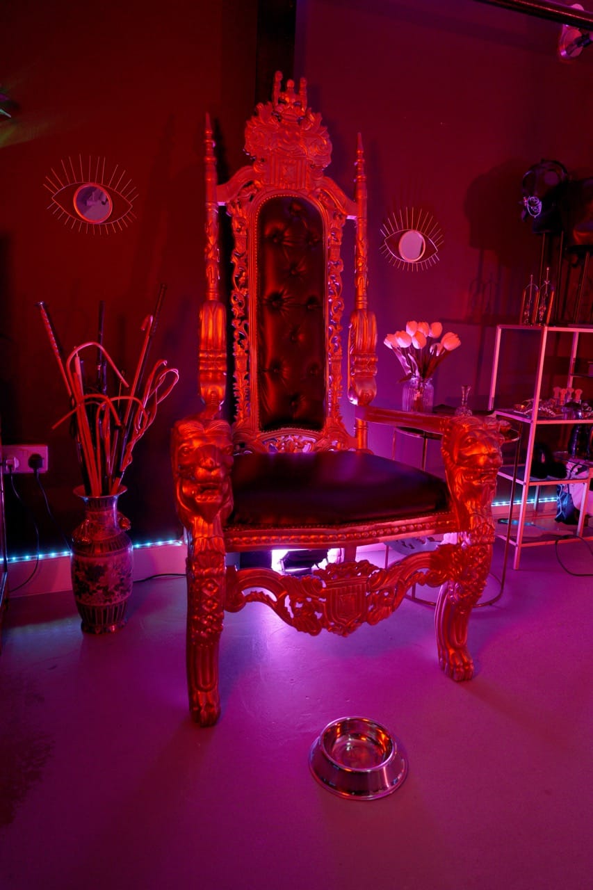 Ornate gilded throne in the dungeon chamber under red and purple light