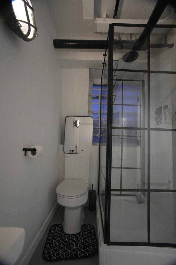 Modern shower room with a black-framed glass screen at London Dungeon Suite