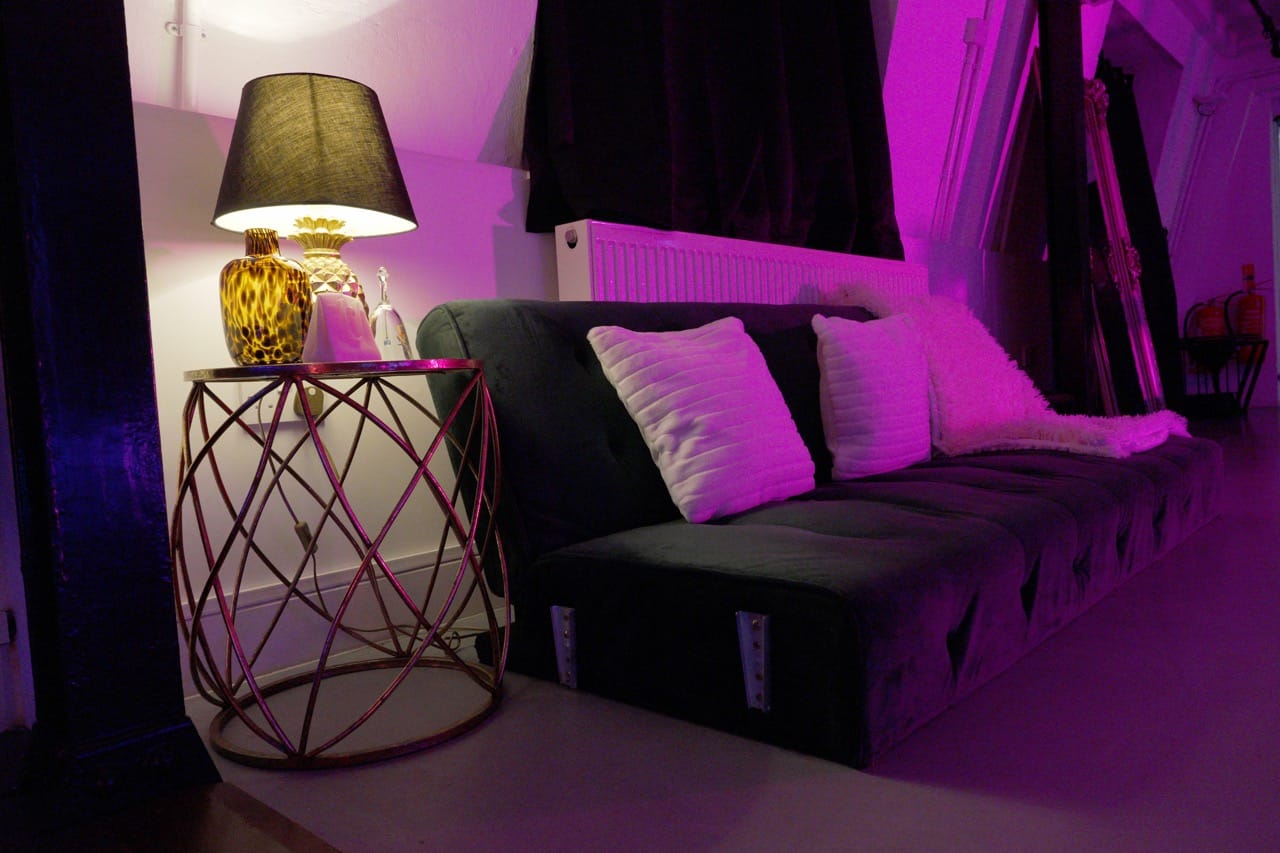 Lounge corner of the penthouse with a velvet sofa and a gold table lamp